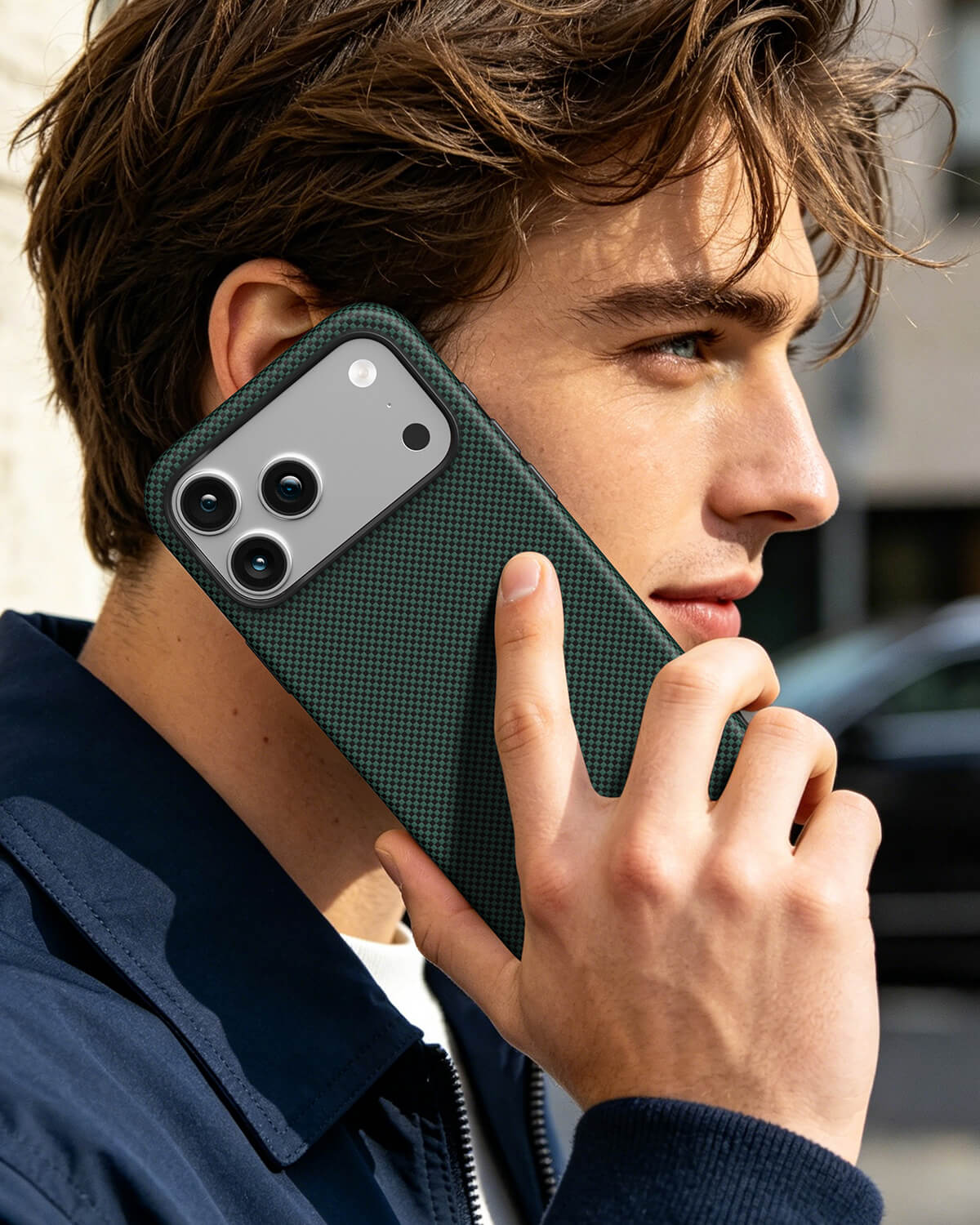 Young man making phone call outdoors with pine green aramid fiber magnetic case